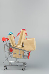 Shopping cart with purchases - packages and boxes on trendy gray background with copy space...