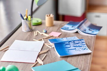 interior, mess and education concept - school supplies scattered on table at home