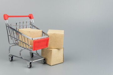 Shopping cart with purchases - packages and boxes on trendy gray background with copy space...