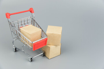 Shopping cart with purchases - packages and boxes on trendy gray background with copy space...
