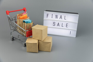 Shopping cart with purchases - packages and boxes on trendy gray background with copy space...