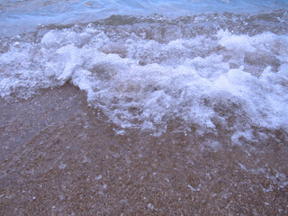 Fototapeta na wymiar Photo by the sea. Landscape. Wet sand, waves and foam.