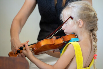 little girl playing small violin, with violin teacher horizontal shape, music lesson