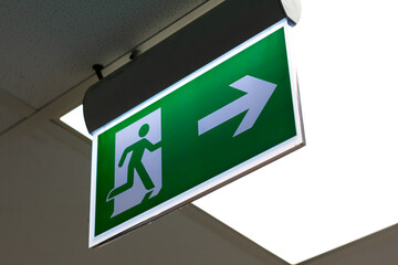 Green fire escape sign hang on the ceiling in the office