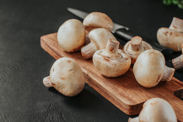 Fresh champignons on a wooden board. Slicing mushrooms.