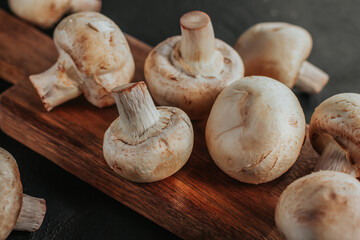 Fresh champignons on a wooden board. Slicing mushrooms.