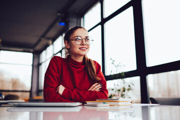 Young attractive blonde female in stylish eyeglasses dreaming whine sitting in loft interior...