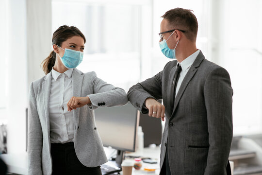 Businessman and businesswoman with medical mask in office. Greetings in Covid-19 time.	
