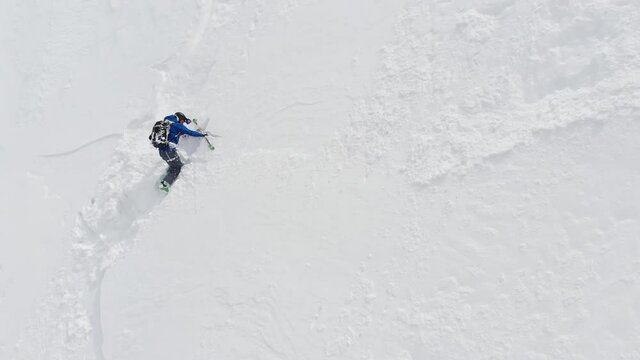 An aerial view of a male athlete athlete skier clambering up a steep slope up. Skitour freeride backcountry climbing with skis through the snow high in the mountains of the North Caucasus
