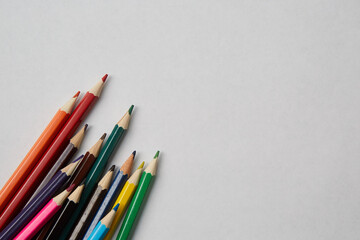 Several colored pencils of various shades lie on a white background, macro photography.