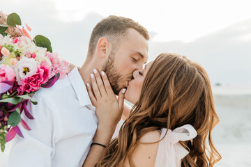 Love Story of a beautiful couple in a pink wedding luxury dress with a bouquet in the Sahara desert, sand, dunes