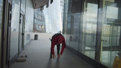 Back view following shot of young man running though walk way between urban buildings, performing front flip, cartwheel and backflip while practicing parkour and freerunning outdoors - Powered by Adobe