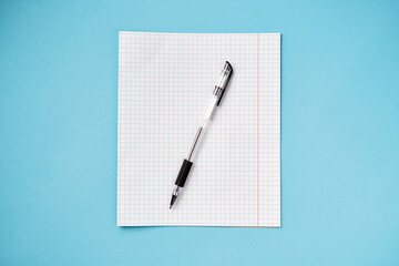 Top view of blank school paper with pen on blue background