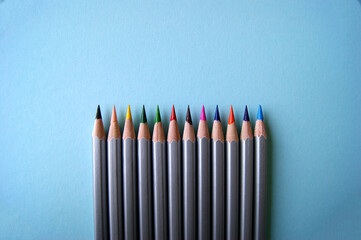 Many color pencils lies on light blue background. Art concept