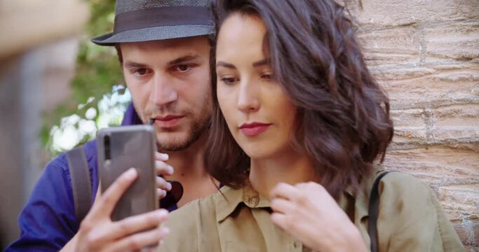Two tourists using smartphone to make a selfie in rural town of Spello. Portrait medium shot. Tro people making a selfie outdoor.Friends italian trip in Umbria.4k slow motion