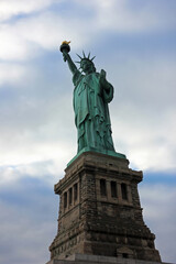 Fototapeta premium Low angle view of New Yorks Statue Of Liberty with grey dark clouds in background upcoming bad weather