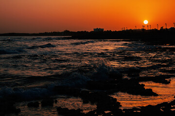 Orange sunset on the sea. Nature background. The Mediterranean sea at sunset. Nature of Cyprus. The sea in the rays of the setting sun.