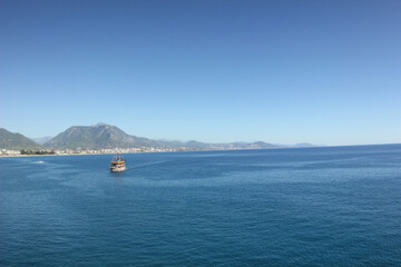 Alanya, TURKEY - August 10, 2013: Travel to Turkey. Rocks, wildlife of Turkey. Clear blue sky. The waves of the Mediterranean Sea. Water surface. Mountains and hills in the distance in the background.