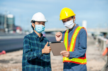 Two engineer talking project construction on site,Man two people a wearing face mask working meeting on tablet at site work place