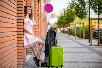 girl with a suitcase on the street. Girl with a suitcase goes on vacation. Girl with a suitcase...