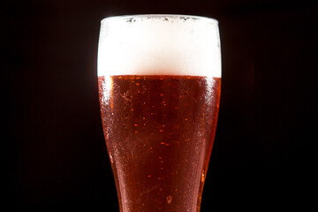 Cold tasty beer on hot summer day. Glass of beer on wooden table on black background