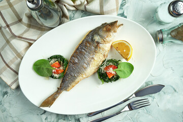 Baked dorado fish with stewed spinach in a white plate. Top view