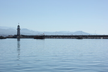 Alanya, TURKEY - August 10, 2013: Travel to Turkey. The waves of the Mediterranean Sea. Water surface. Port. Ships on the water. Boats at sea. Yachts and other water transport. Lighthouse. Mountains i