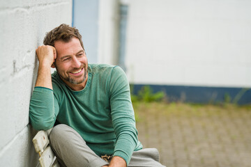 sexy Mann sitzt entspannt auf einer Bank und lacht 