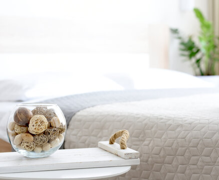 Decor items, wooden round balls on a tray by the bed in the bright interior of the room. Calm milimalistic interior.