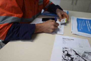 Safety workplace construction worker setting on a chair holding a pen signing of site safety...