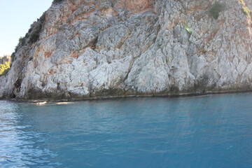 Alanya, TURKEY - August 10, 2013: Travel to Turkey. The waves of the Mediterranean Sea. Water surface. Mountains and hills on the coast of Turkey. Port. Green hills.