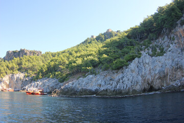 Fototapeta na wymiar Alanya, TURKEY - August 10, 2013: Travel to Turkey. The waves of the Mediterranean Sea. Water surface. Mountains and hills on the coast of Turkey. Port. Green hills.