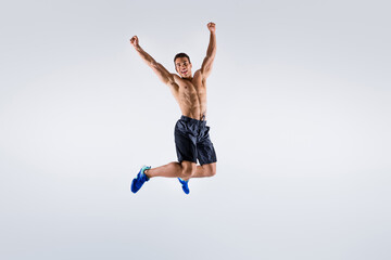Fototapeta na wymiar Full size photo of handsome sportsman dark skin guy naked chest jump high up celebrate competition winning raise arms up wear shorts sneakers isolated white color background
