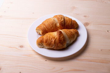 a white ceramic cup with black espresso, french croissant as breakfast or snack concept on rustic, natural texture wooden surface