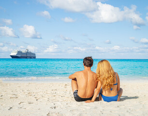 Young couple sitting on the beach. Honeymoon on the island