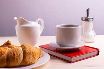 a white ceramic cup with black espresso, french croissant as breakfast or snack concept on rustic, natural texture wooden surface