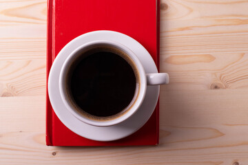 a white ceramic cup with black espresso, french croissant as breakfast or snack concept on rustic, natural texture wooden surface