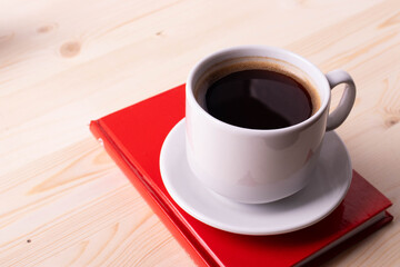 a white ceramic cup with black espresso, french croissant as breakfast or snack concept on rustic, natural texture wooden surface
