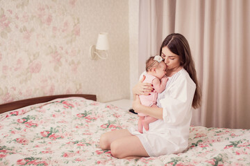 Obraz na płótnie Canvas A young mother rocks her kid and sings a lullaby at home. A restless Child does not sleep. Caring for newborn motherhood. Mother's love. Nanny. Tired woman. Rest sleep insomnia. mom holds baby in arms