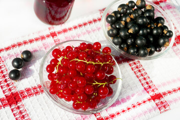 Fresh red and black currants in bowl ,syrup in a glass bottle on table close up