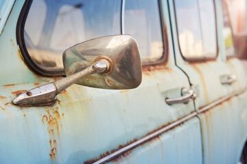 Rear view mirror of an old rusty turquoise car