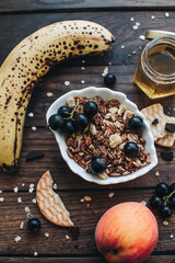 Healthy breakfast ingredients. Homemade granola, oatmeal, yogurt in the bottle, honey, berries and fruits on a wooden background. Morning aesthetics and beautiful layout on a wooden table.