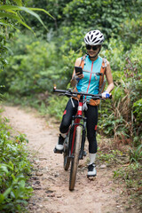 Fototapeta na wymiar Cyclist use smartphone when riding mountain bike on forest trail.