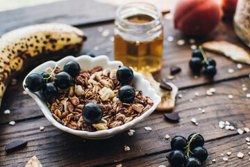 Healthy breakfast ingredients. Homemade granola, oatmeal, yogurt in the bottle, honey, berries and fruits on a wooden background. Morning aesthetics and beautiful layout on a wooden table.