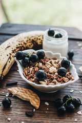 Healthy breakfast ingredients. Homemade granola, oatmeal, yogurt in the bottle, honey, berries and fruits on a wooden background. Morning aesthetics and beautiful layout on a wooden table.