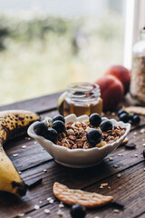 Healthy breakfast ingredients. Homemade granola, oatmeal, yogurt in the bottle, honey, berries and fruits on a wooden background. Morning aesthetics and beautiful layout on a wooden table.