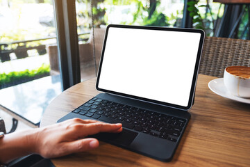 Mockup image of a woman touching on tablet touchpad with blank white desktop screen as a computer pc with coffee cup on the table