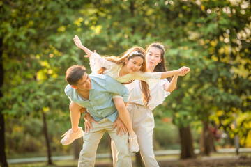 Fototapeta premium Happy family playing on the grass in the park at sunset. The concept of a happy family.