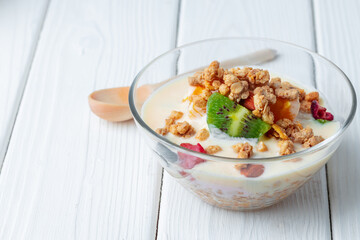 Tasty breakfast with granola, yoghurt and fruits in a glass bowl