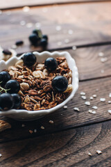 Healthy breakfast ingredients. Homemade granola, oatmeal, yogurt in the bottle, honey, berries and fruits on a wooden background. Morning aesthetics and beautiful layout on a wooden table.